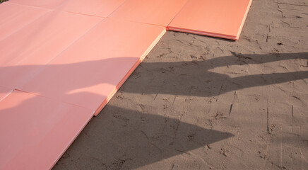 The polyplex polystyrene slab is laid on wet sand as insulation for the foundation of an outdoor swimming pool