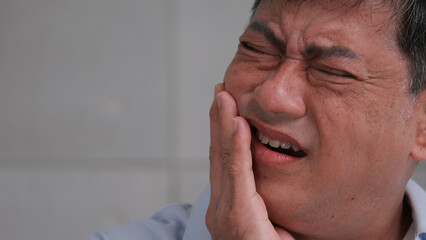 Asian senior man suffering from toothache.