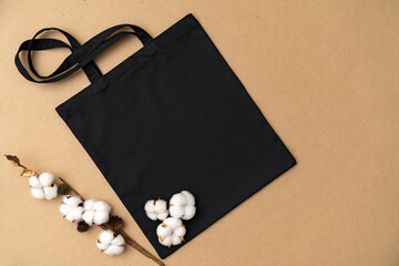 Textile eco bag and cotton flowers on paper background.