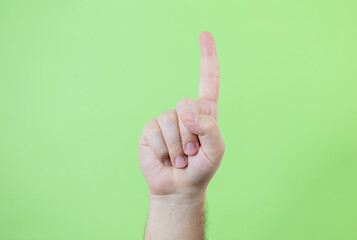 A man making hand signals on green background.
