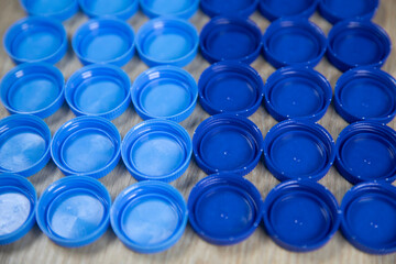 Blue plastic bottle caps isolated on wood background.