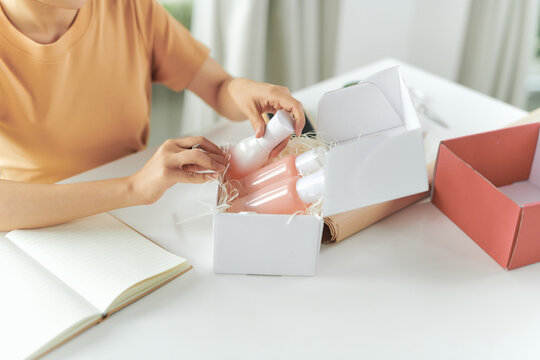 Cropped Image Of Woman Hands Packing Shipment With Set Skincare Products In Box For Delivery