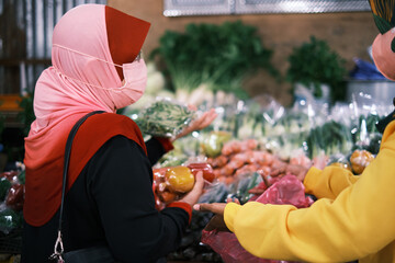 CAMERON HIGHLANDS, PAHANG, MALAYSIA-CIRCA JUNE 2022: Unidentified Muslim lady with face mask buys...
