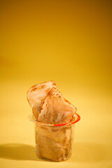 plastic drinking glass full with used tea bags. copy space. yellow background
