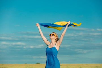 Girl with Ukrainian flag in wheat field