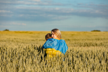 Naklejka na ściany i meble Mother with son in ukrainian flag in wheat field