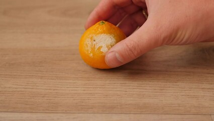 Close-up of a rotten tangerine with mold on a light wooden background. Spoiled fruit.