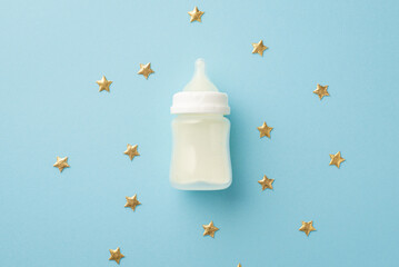 Baby accessories concept. Top view photo of milk bottle and gold stars on isolated pastel blue background