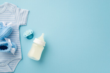Baby boy concept. Top view photo of blue infant clothes bodysuit knitted booties soother and milk bottle on isolated pastel blue background with copyspace
