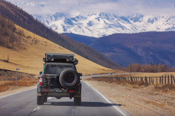 Travel road with car 4x4 mountains Altai with snow hill and autumn forest