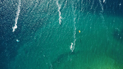 Aerial drone view of windsurfers and kite surfers enjoying on blue sea ocean waves..