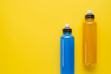 Isotonic energy drink. Bottle with blue and yellow transparent electolytes liquid, sport beverage on a yellow background. It usually contains salt and sugar and maintains optimal hydration