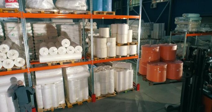 The forklift puts the goods on the shelf of the warehouse. The forklift puts the nonwovens on the shelf of the factory warehouse. Warehouse at the nonwovens factory.