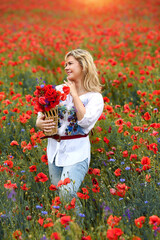 Naklejka na ściany i meble А happy young a woman in a white shirt with a floral print and jeans holding a wallet with poppies in her hands. Summer concept
