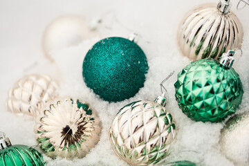 Christmas decorations close up. beautiful shiny balls of green and gold on white snow. holiday...