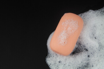 Pink soap and white soap foam on black background. Copy space for text.
