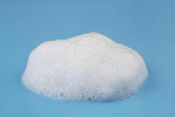 White foam bubbles on blue background. Purity and softness concept.	
