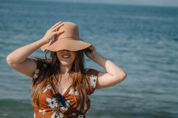 young plus size woman putting on her hat on the beach