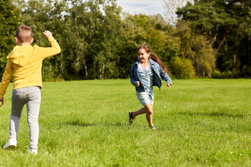 Fototapeta premium childhood, leisure and people concept - happy children playing tag game and running at park