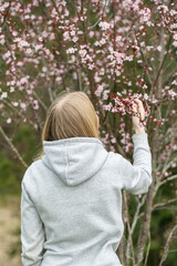 A young blonde woman smelling cherry blossom