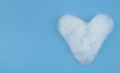 Obraz premium Heart from foam bubbles on blue background with room for text. Softness and love concept.