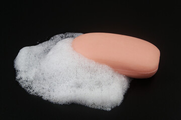 Pink soap with foam bubbles on black background.	
