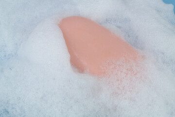 Pink soap bar on white foam close-up