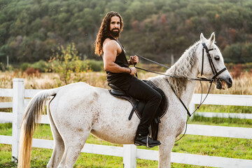 Hunky cowboy. Young muscular guy in t-shirt on horseback. Man riding a horse. Hunky cowboy rides...