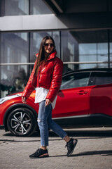 Fototapeta na wymiar Woman standing by her new red car