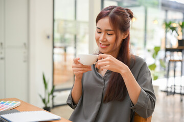 Relaxed young asian woman enjoy sipping morning coffee in the comfortable coffee shop.
