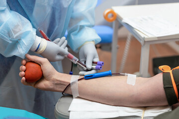 bone marrow donation. male hand holding red ball, man with blood transfusion system, blood bag. soft focus - obrazy, fototapety, plakaty