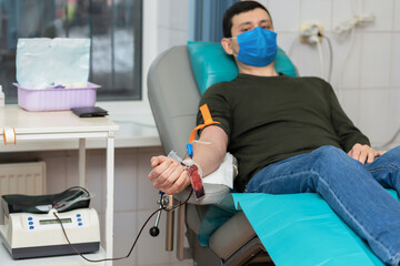 bone marrow donation. man in medical mask, male hand holding red ball, blood transfusion system,...