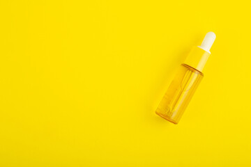 glass yellow bottle with pipette with essential oil on a yellow background top view. Aromatic cosmetic product for skin  hair care Moisturizing beauty product with vitamin C close up