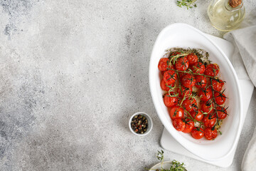 Cherry Tomatoes baked with spices, garlic, herbs ,garlic, olive oil in a white dish. Top view, copy...