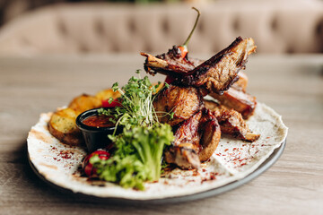 Fried ribs with rosemary, rustic potatoes, onions, sauce on a plate. Place for text, copy space