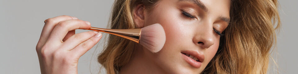 Half-naked white ginger woman doing makeup with powder brush