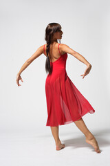 Young modern ballet woman dancer dancing on gray studio background