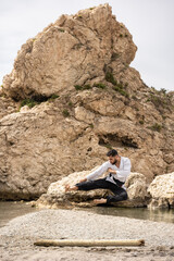karate expert in kimono performing a flying kick on the beach next to a mound with a log under it