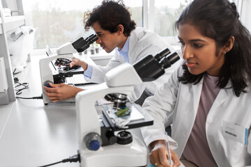 science research, work and people concept - international team of scientists with microscopes...