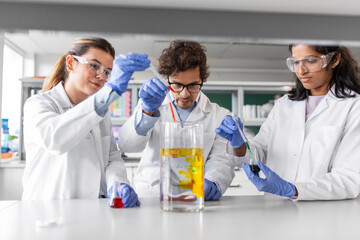 science research, work and people concept - international team of scientists with chemicals working...