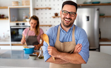 Portrait of handsome happy man cooking at home preparing food in kitchen.