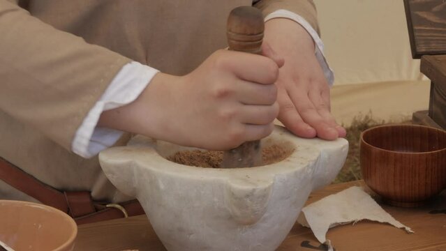 hand with pestle grinds seeds into powder inside the mortar