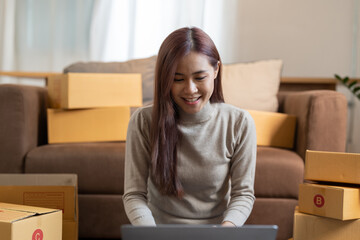 Asian woman entrepreneur using laptop for checking order, online market packing box delivery,Startup successful small business owner,SME, concept