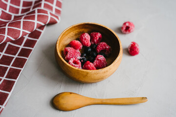 Juicy frozen berries in a wooden plate.