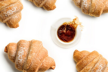 Cup with coffee and croissants isolated on white background. Coffee spills out of the cup.