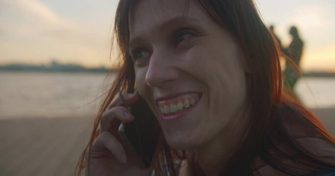 Woman talking on phone with friends and smiling, outdoors close-up