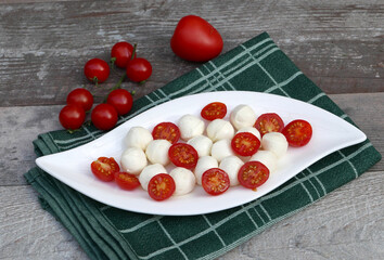 Naklejka na ściany i meble Mozzarella-Käse mit Basilikum und Tomaten auf einem Teller.