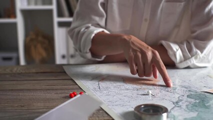 The hand of a young white girl tourist traveler chooses a point on the world map where he would go on his vacation summer adventure travel and vacation world map compass
