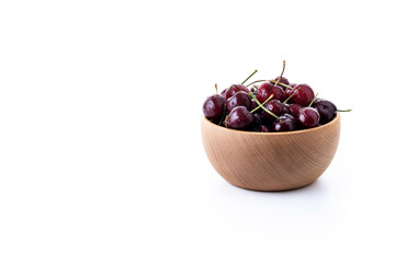 Fresh cherries with water drops in wooden bowl isolated on white background. Copy space