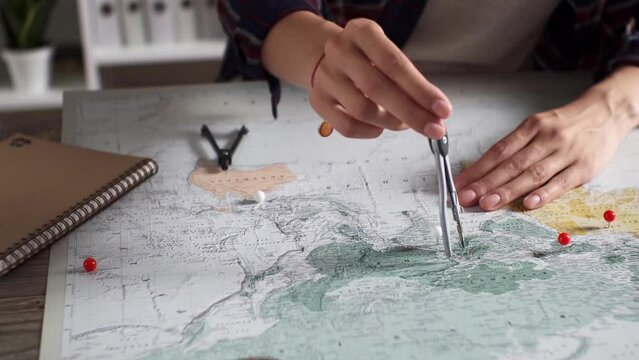 A traveler girl measures distances between points on a map, measuring the distance on a map with a compass, a fanatical traveler tourist plans a trip on a map with measurement devices
